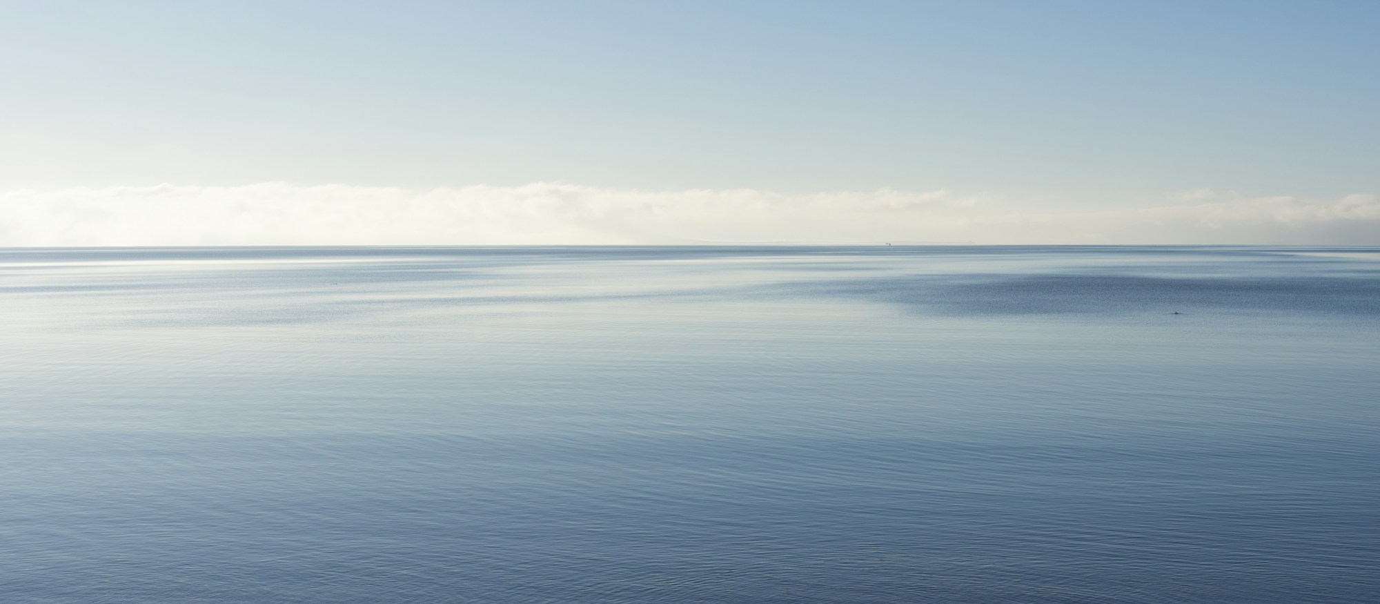 A calm Atlantic horizon off Galway with soft blue water and a pale sky