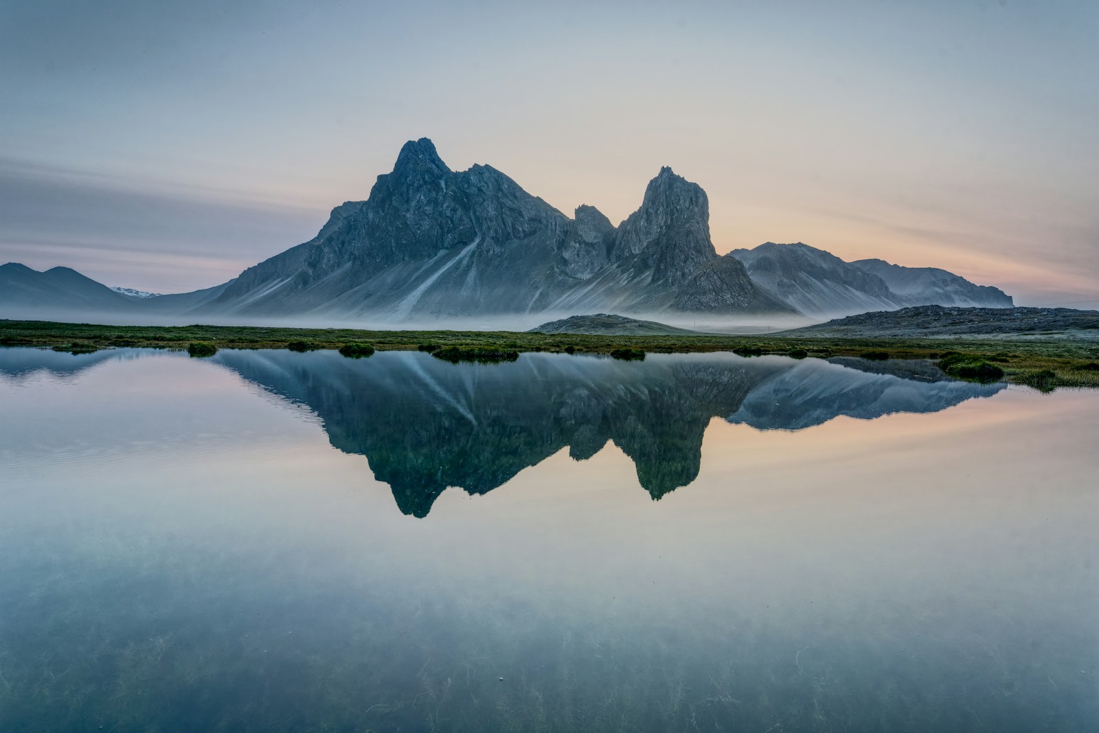 Mountains reflected in a still, misty lake in Iceland